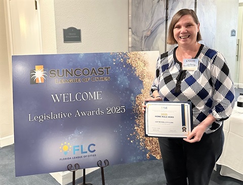 woman holding certificate in front of sign