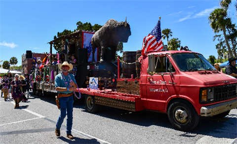 man with cowboy hat throwing beads by parade float