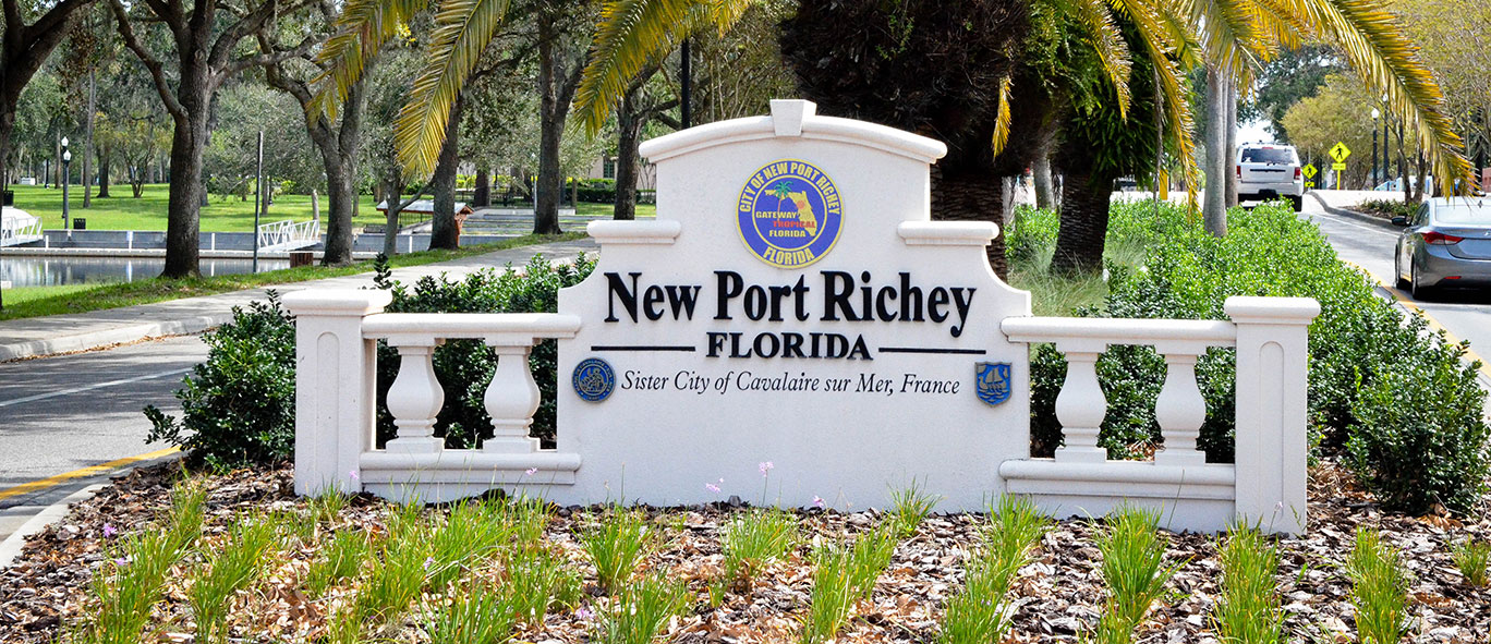 New Port Richey city sign in concrete. Text reads "New Port Richey, FL. Sister city to Cavalaire sur Mer, France"