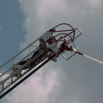 A firefighter on the ladder putting out a fire