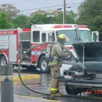A firefighter putting out a vehicle engine fire