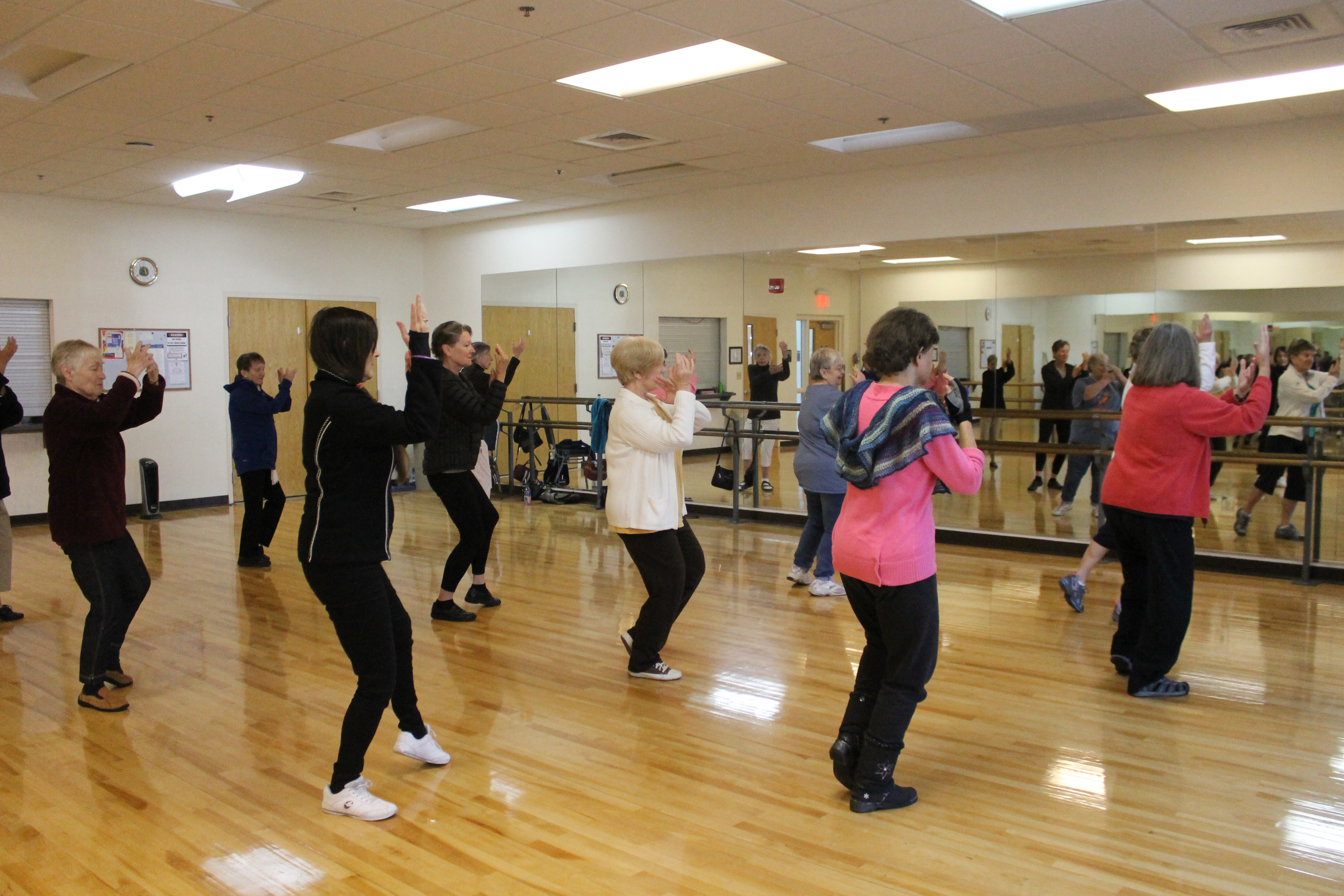 Several people in a dance studio performing synchronized exercises